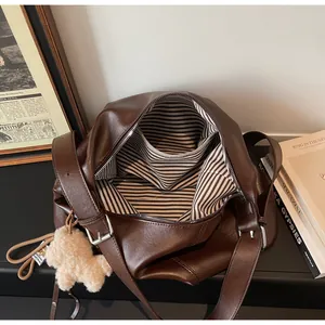 Vue détaillée du grand sac à main marron foncé avec doublure rayée et charme de chien