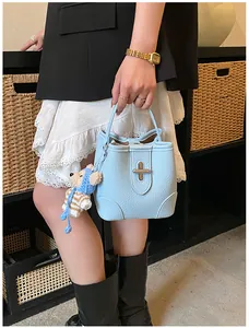 Detail of light blue pebble leather bucket bag with cute bear charm and metal lock