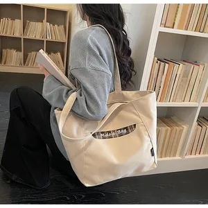 Dettaglio della borsa tote in tela con tasca scozzese marrone in un contesto universitario