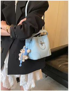 Detail of light blue bucket bag with lychee grain leather and cute teddy bear charm