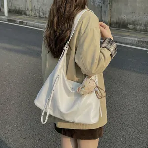 Sac bandoulière minimaliste en cuir blanc avec breloque peluche en vue extérieure
