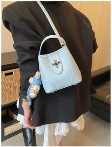 Detail of light blue lychee pattern bucket bag with silver lock and teddy bear charm