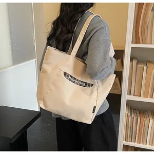 Dettaglio della borsa tote in tela con tasca a quadri e logo del brand