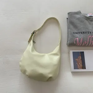 Detail view of adjustable strap and smooth texture on light yellow crescent hobo bag