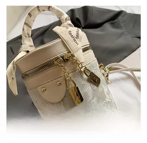 Dettaglio della borsa a secchiello beige con pizzo e chiusura in metallo dorato