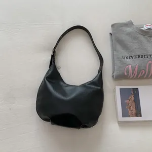 Macro detail of black crescent hobo bag with grainy texture and silver metal hardware