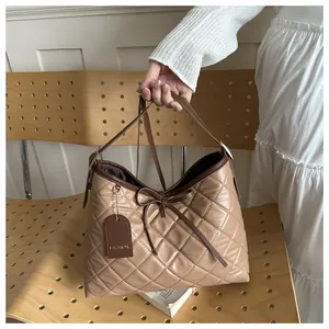 Close-up of khaki quilted tote bag with bow detail and glossy synthetic leather texture