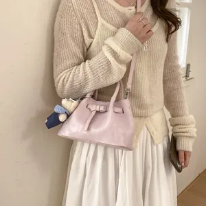 Detail of pale pink bucket bag with decorative belt and cute teddy bear charm