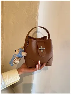 Brown bucket bag detail with lychee texture leather, silver swivel lock and bear charm