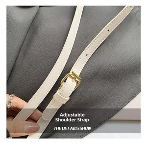 Close-up of adjustable cream PU leather shoulder strap with golden metal buckle
