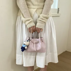 Detail of light pink leather bucket bag with silver buckle and cute teddy bear charm