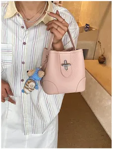 Detailed close-up of a pink litchi texture bucket bag with a cute bear charm on a model