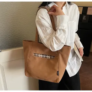 Vista laterale di una borsa tote in tela a quadri portata a spalla da una donna