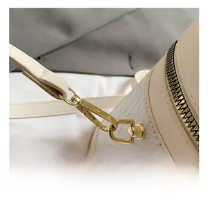 Detail of golden metal hook and floral embossed texture on cream bucket bag side