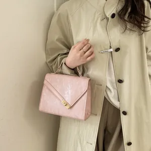 Detail showing the pink pleated texture and gold turn-lock closure of the small handbag