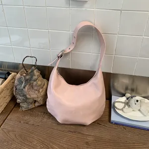 Close-up of a light pink hobo bag featuring adjustable wide straps and metal eyelet details