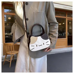 Detailed view of cat-shaped crossbody bag with contrast stitching and ring handle