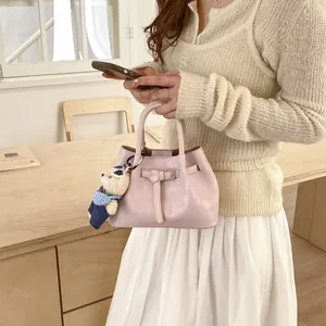 Detail of light pink bucket bag with silver buckle and cute teddy bear charm accessory