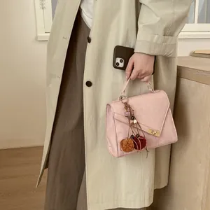 Detail of light pink crossbody bag featuring vertical texture and golden square turn-lock