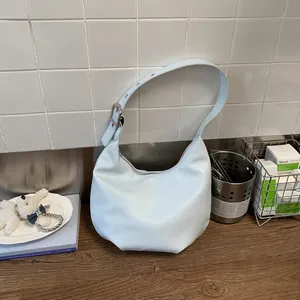Light blue Hobo shoulder bag with leather texture and silver buckle on a wooden surface
