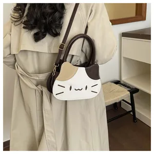 Detail of a cat-shaped crossbody bag featuring tricolor patchwork and embroidered kitten face