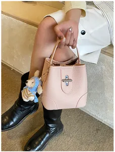 Detail of pink lychee leather bucket bag with metal cross lock and cute bear charm