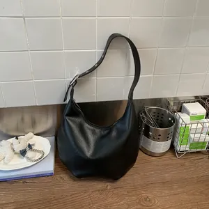 Detail of black crescent hobo bag with soft PU leather texture and silver buckle