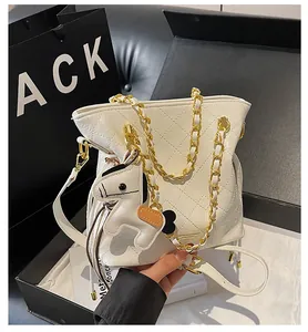 Detail of quilted white bucket bag with golden chain and horse charm accessory