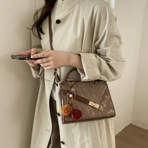 Close-up of vintage brown textured crossbody bag with gold twist lock and colorful charms