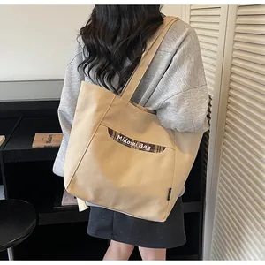 Dettaglio della borsa tote in tela con tasca a scacchi e logo in un interno caldo
