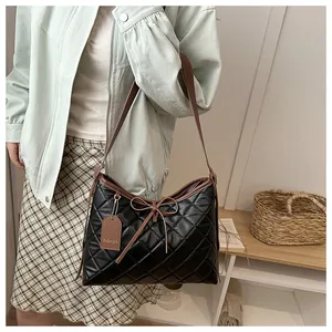 Detail of black quilted shoulder bag featuring brown bow accent and a fashion tag