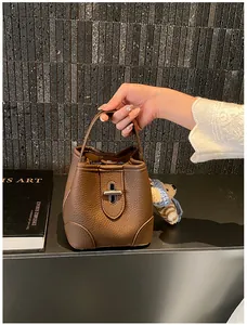 Close-up of brown pebbled leather bucket bag with silver lock and teddy bear charm