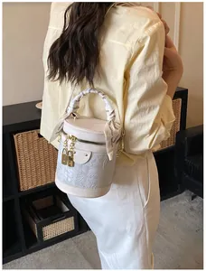 Dettaglio di una borsa a secchiello beige con manico in seta floreale e lucchetto dorato
