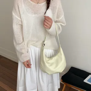 Minimalist beige hobo crescent shoulder bag for women styled with a knitted sweater