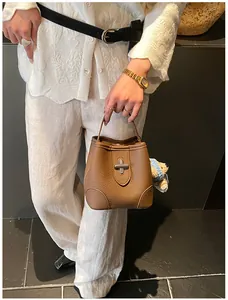 Detail view of brown pebbled leather bucket bag with silver clasp and bear charm