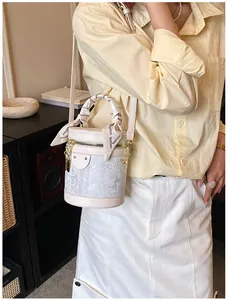 Close-up of cream bucket bag with floral lace detail and elegant silk scarf handle