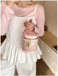 Dettaglio della borsa a secchiello in pizzo rosa con manico in seta e lucchetti d'oro