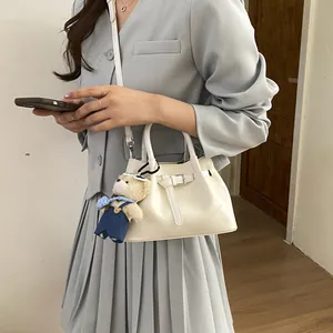 Chic cream bucket bag with belt buckle detail and cute blue bear plush charm