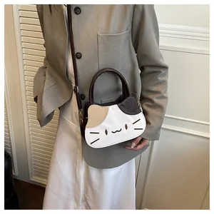 Detail view of a cat-shaped crossbody bag with tricolor stitching and cat face embroidery