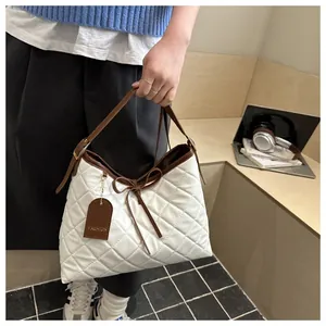 Close-up of white quilted tote bag with brown trim, bow detail and Fashion tag accessory