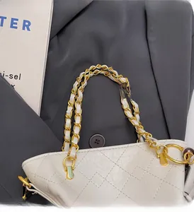 Macro shot of cream quilted leather bag with woven gold chain and leather handle