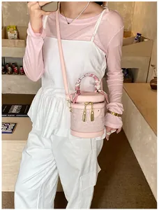 Dettaglio borsa a secchiello rosa con pizzo floreale e manico decorato con foulard di seta