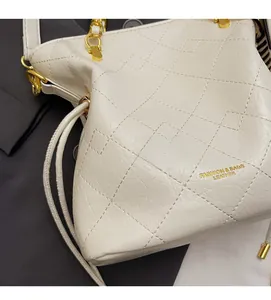 Detailed close-up of white quilted bucket bag with gold chain and litchi texture