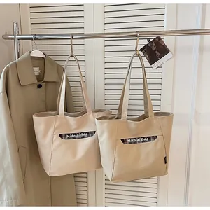 Dettaglio borse tote in tela beige con tasca a quadri e scritte Midolai Bag