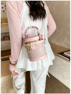 Dettaglio della borsa a secchiello in pizzo rosa con trama floreale e foulard di seta