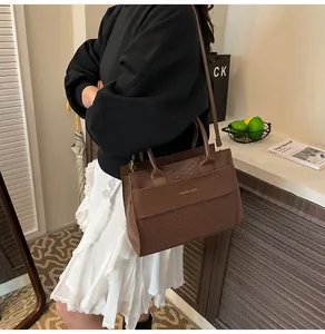 Dettaglio della borsa marrone scuro con texture a coccodrillo e scritta dorata FASHION & BAGS