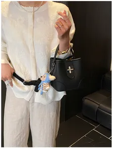 Close-up of black bucket bag with silver clasp and cute bear charm pendant