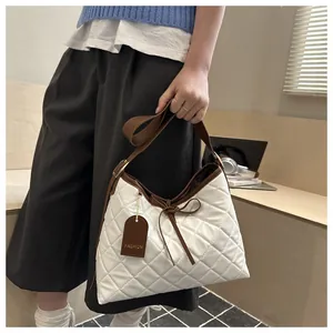 Detail of white quilted tote bag featuring brown bow accent and leather fashion tag