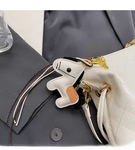 Detail of white quilted bucket bag featuring a cute dog charm and golden chain strap