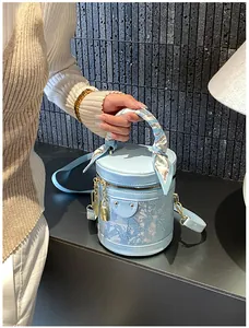 Dettaglio della borsa a secchiello azzurro cielo con manico in seta e chiusura dorata